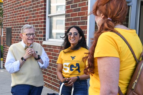 President Gee talks with students wearing gold Student Government Association T-shirts