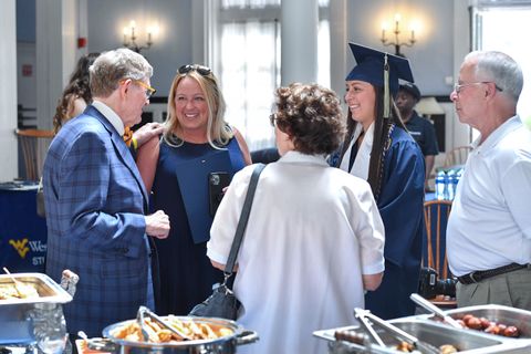 President Gee talks with family members and a graduate at the reception.
