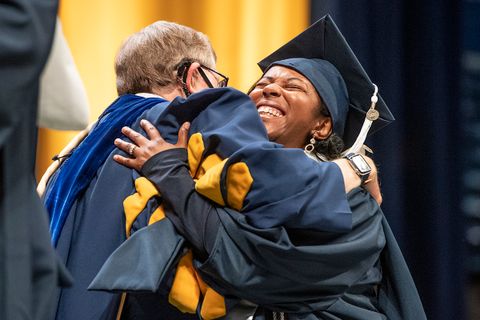 President Gee hugs a graduate as they cross the stage at Commencement.