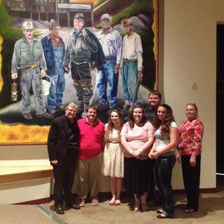 President Gee stands with HSTA students in front of a coal mining mural