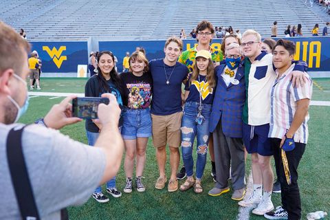 President Gee poses for photo with group of students on Mountaineer Field