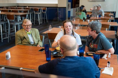 President Gee sits at a dining hall table with a family