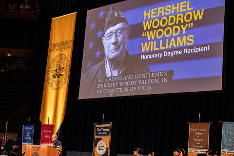 Slide honoring Hershel "Woody" Williams shows on screen at Commencment