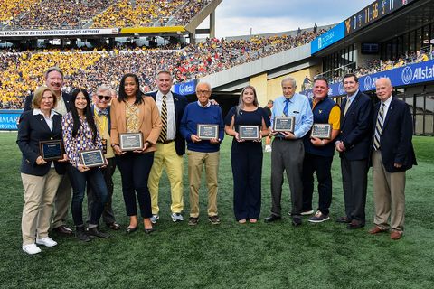 Alumni award winners pose for a group picture on the sidelines at Milan Puskar Stadium